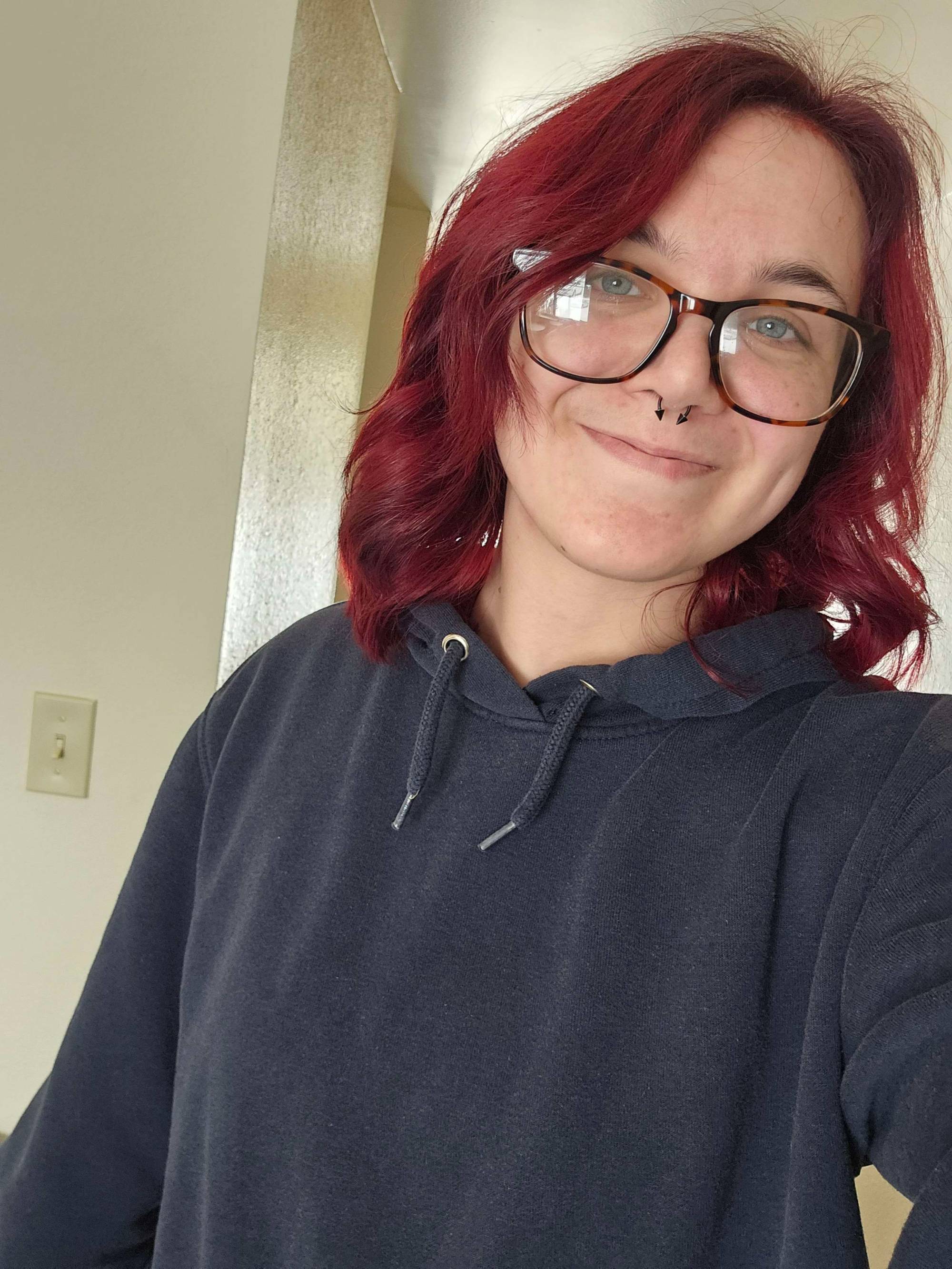 Girl with glasses and curly red hair smiling at the camera